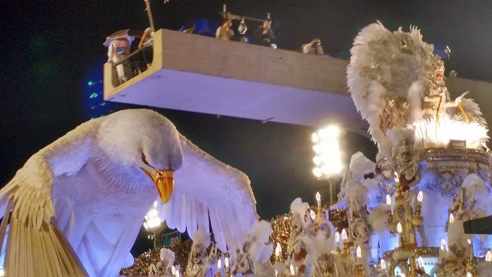 Carro alegórico da Portela com uma grande águia branca iluminada num desfile no Sambódromo