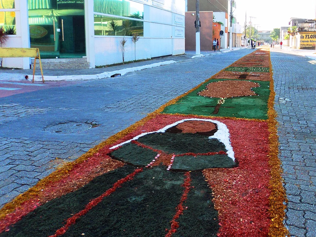 Tapete colorido de serragem com tema religioso montado na rua para a procissão de Corpus Christi em Coronel Fabriciano, Minas Gerais