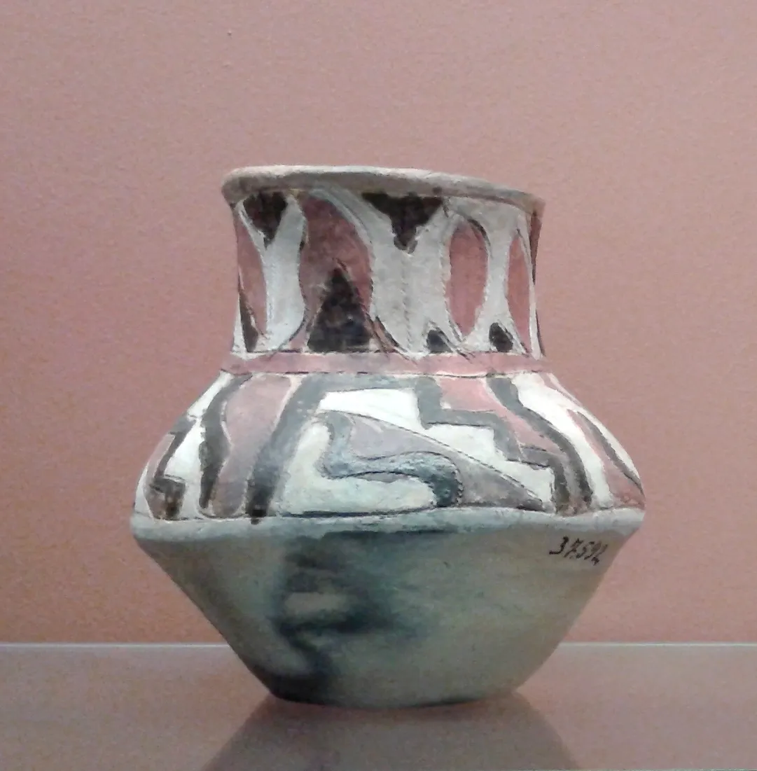Vaso de cerâmica Kadiwéu com desenhos geométricos em branco, preto e rosa, exposto numa vitrine de museu