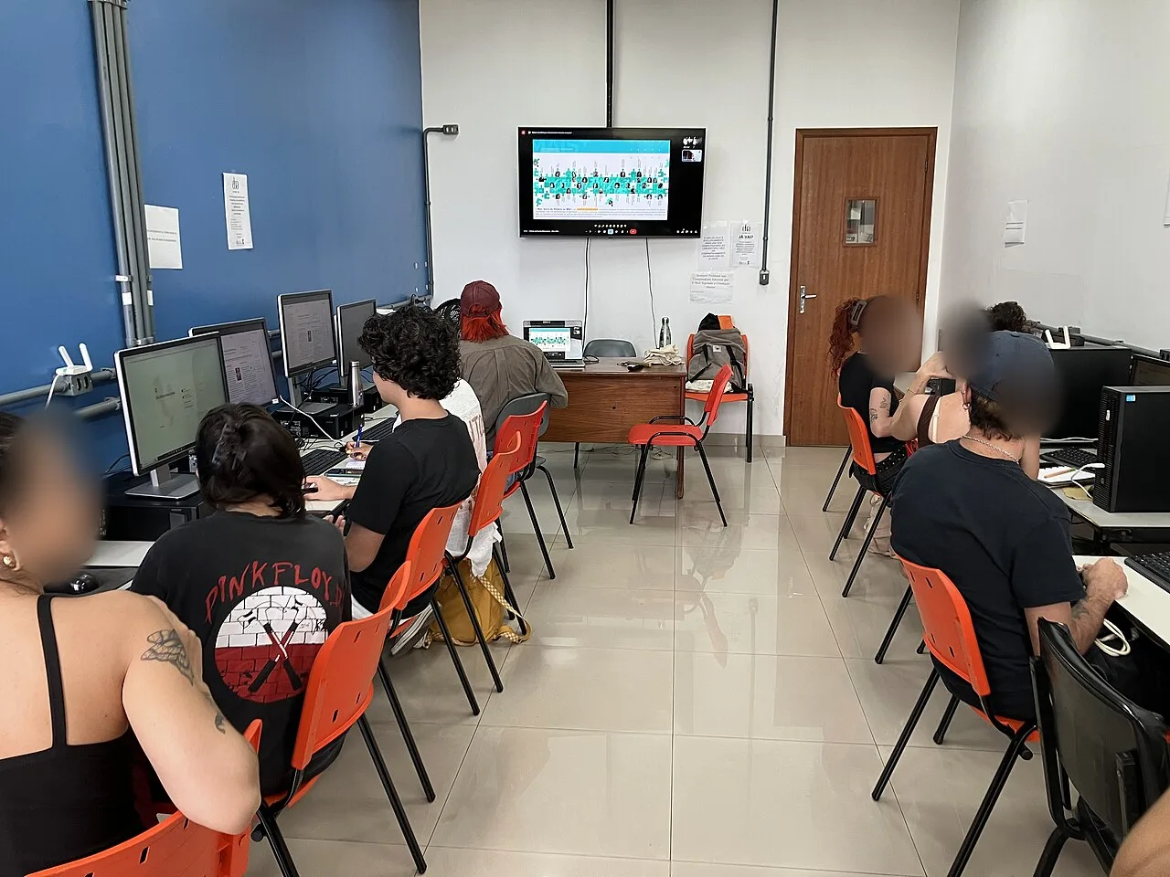 Estudantes de costas diante dos computadores em laboratório da UFRJ, universidade pública