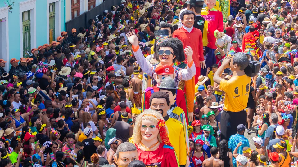 Multidão fantasiada e bonecos gigantes numa ladeira de Olinda na terça-feira de Carnaval