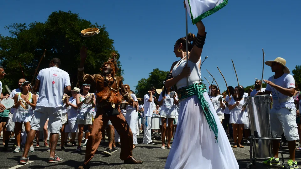 Bloco de Carnaval de rua em São Paulo, com porta-estandarte, ritmistas e foliões na avenida
