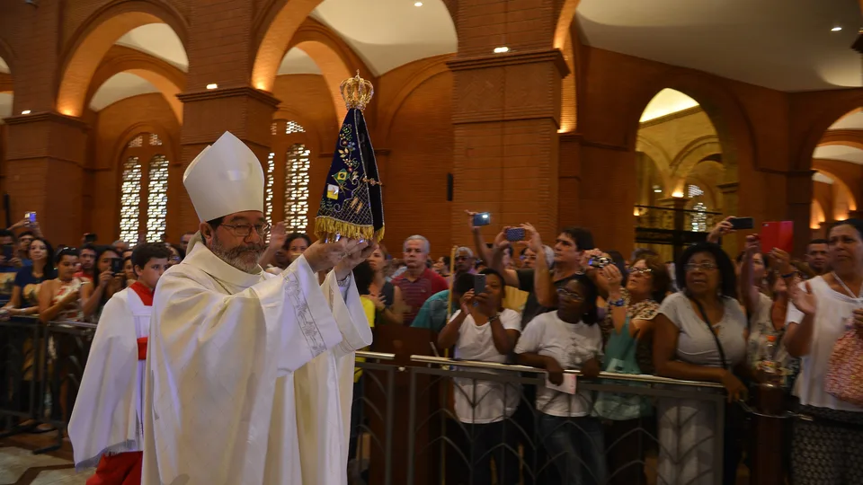 Bispo carrega a imagem de Nossa Senhora Aparecida diante dos fiéis no Santuário Nacional, no dia 12 de outubro