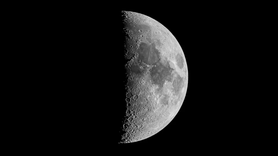 Meia-lua do quarto crescente, com metade do disco iluminada e crateras nítidas na linha de sombra