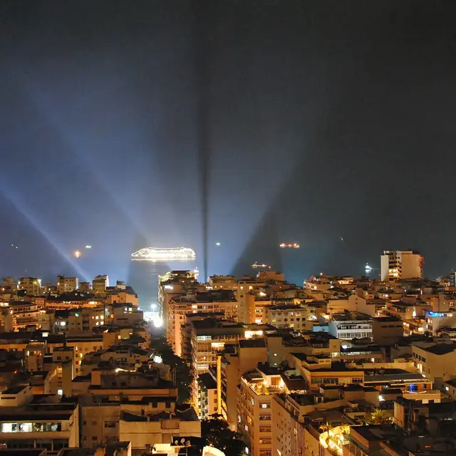 Vista noturna de Copacabana na noite de Réveillon, com feixes de luz no céu