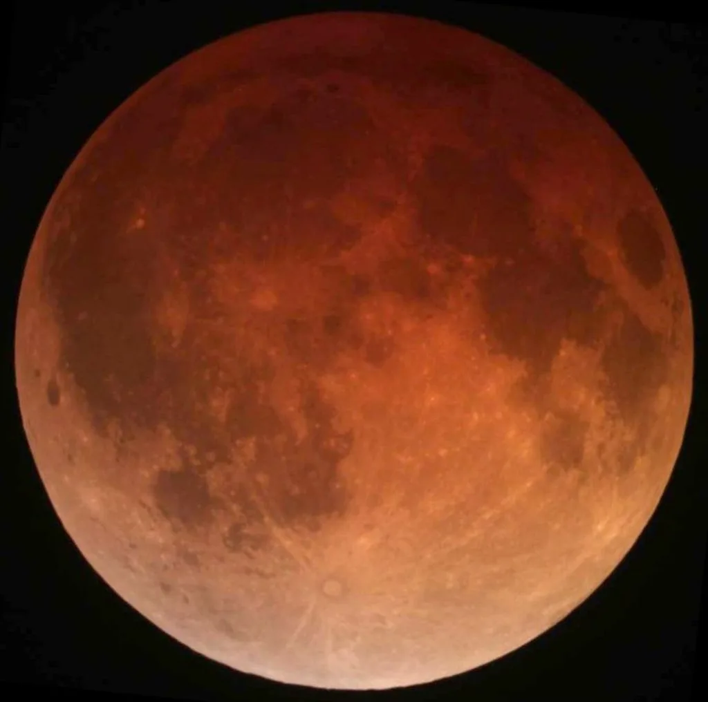 Eclipse lunar total de abril de 2014 com a Lua adquirindo tonalidade avermelhada característica devido à refração atmosférica terrestre.